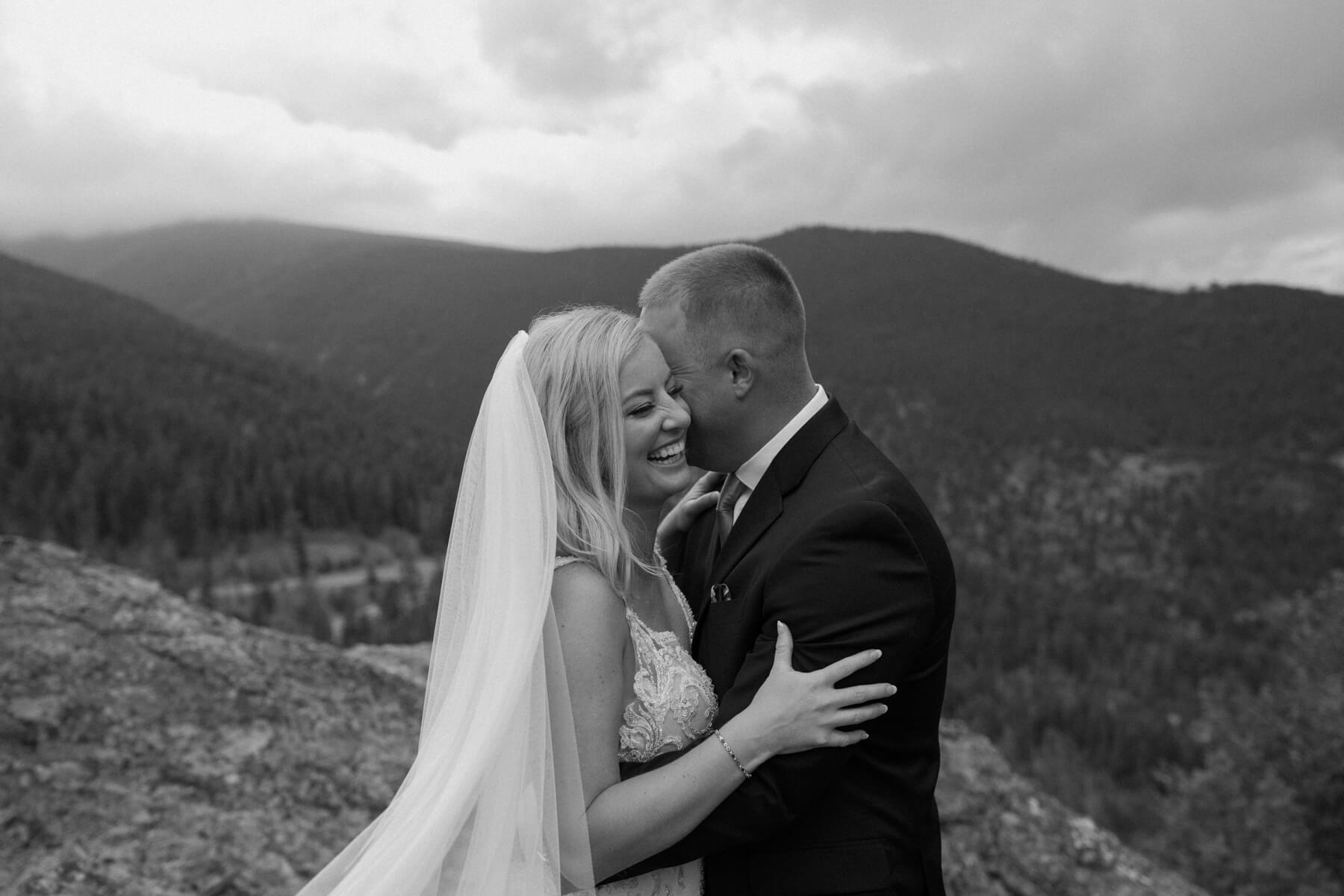 Bride and groom laughing while hugging in front of mountains at idaho springs wedding venue | McArthur Weddings and Events