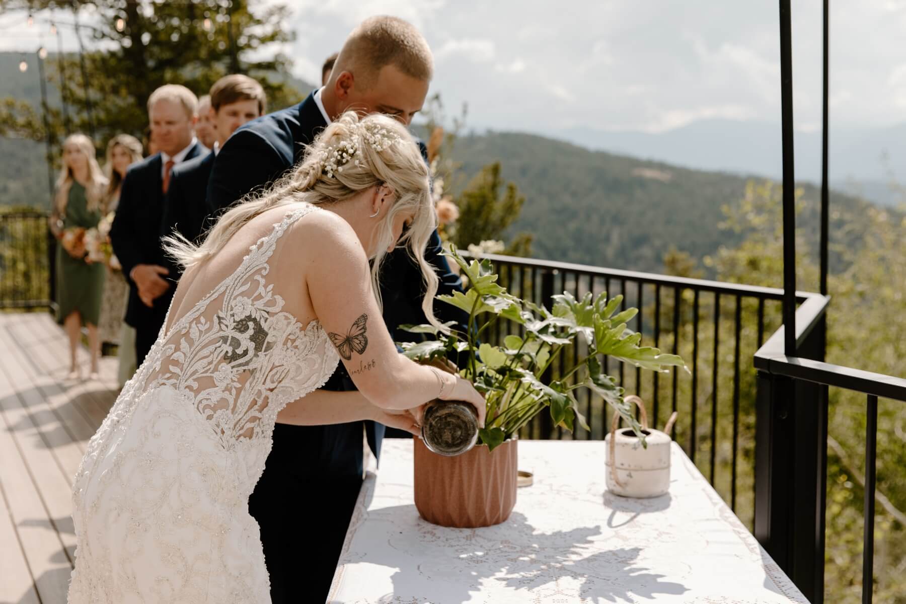 Bride pouring dirt into pot during unity plant potting during wedding ceremony | McArthur Weddings and Events