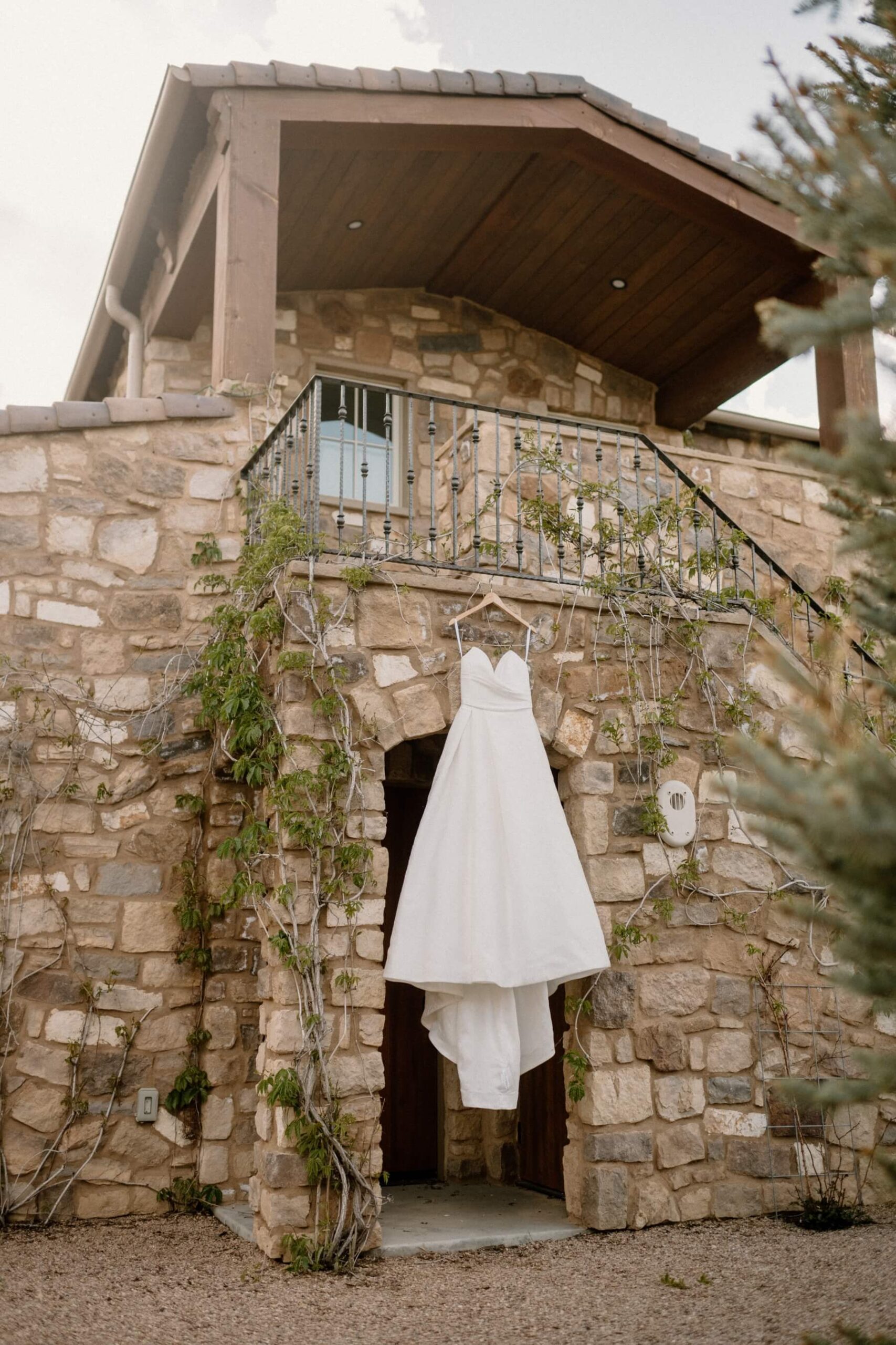 Wedding dress hanging from iron railing on stone house