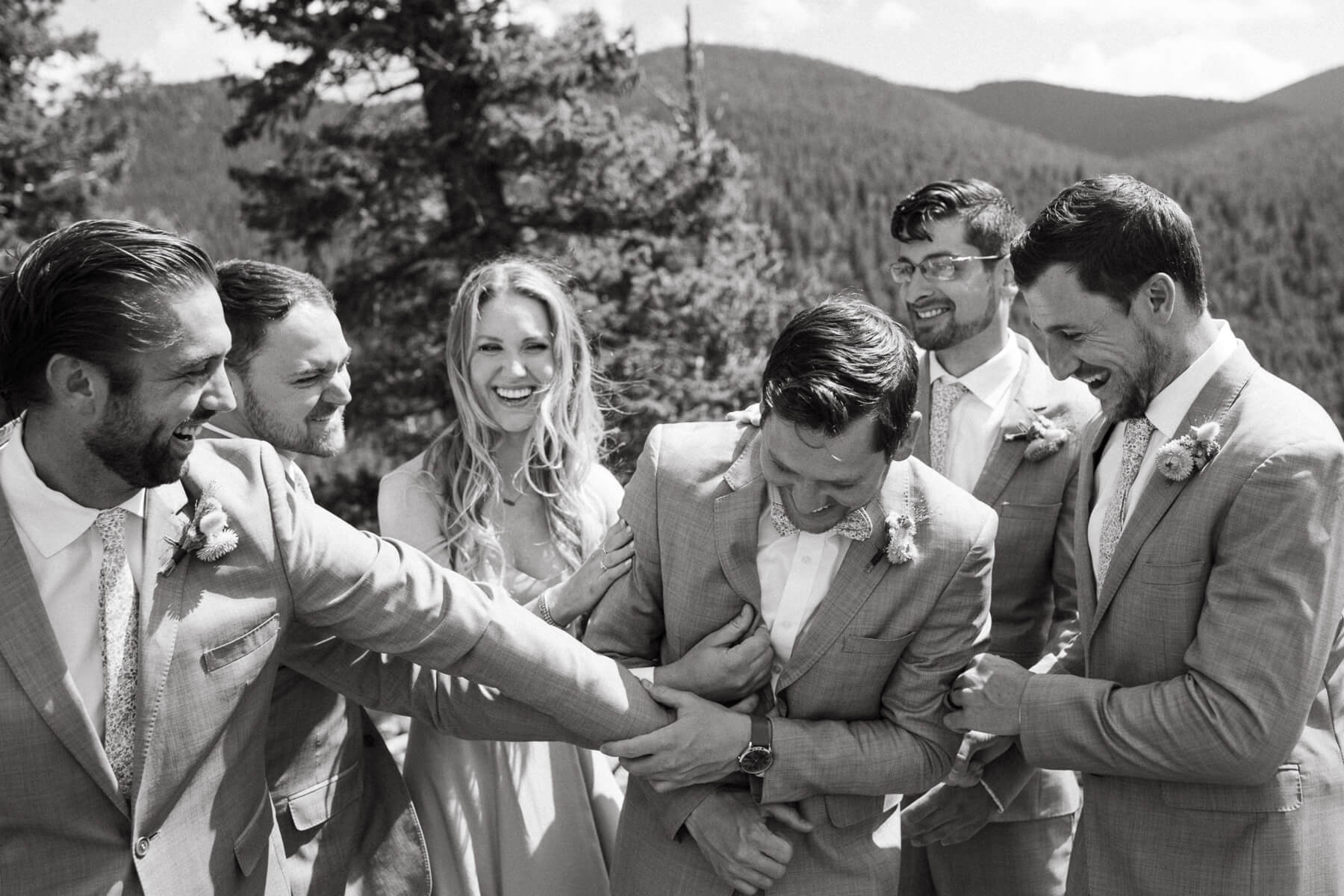 Groom laughing with groomsmen and sister during at North Star Gatherings, a Colorado mountain wedding venue
