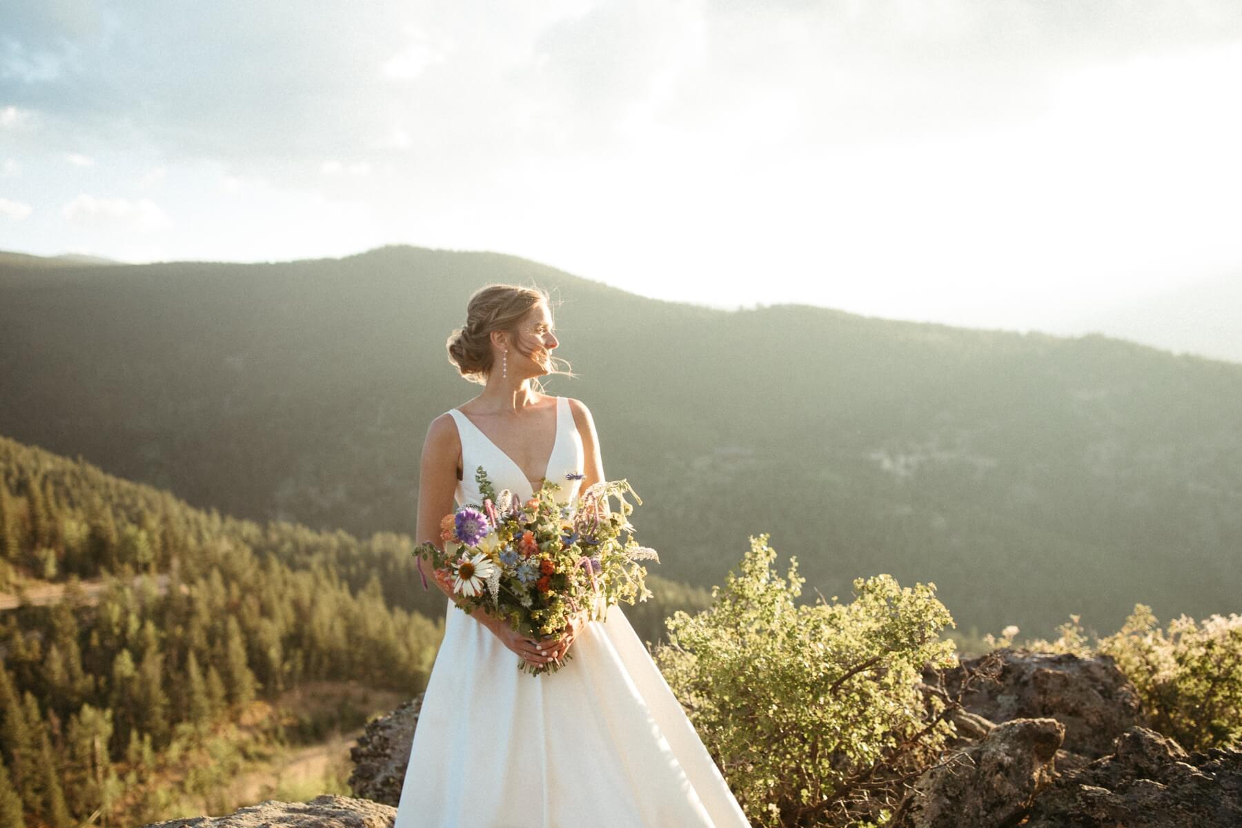 Bride holding a hand tied bouquet while looking off into the distance at North Star Gatherings, a Colorado mountain wedding venue