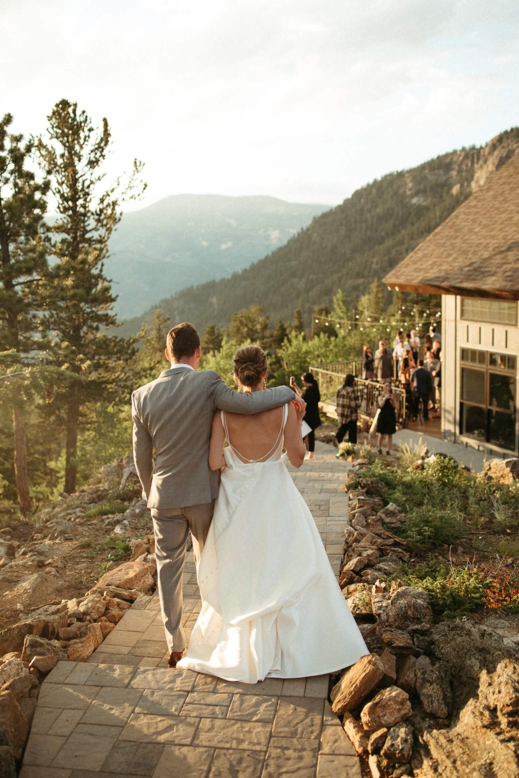Groom walking with his arm over bride's shoulder back to reception at North Star Gatherings, a Colorado mountain wedding venue