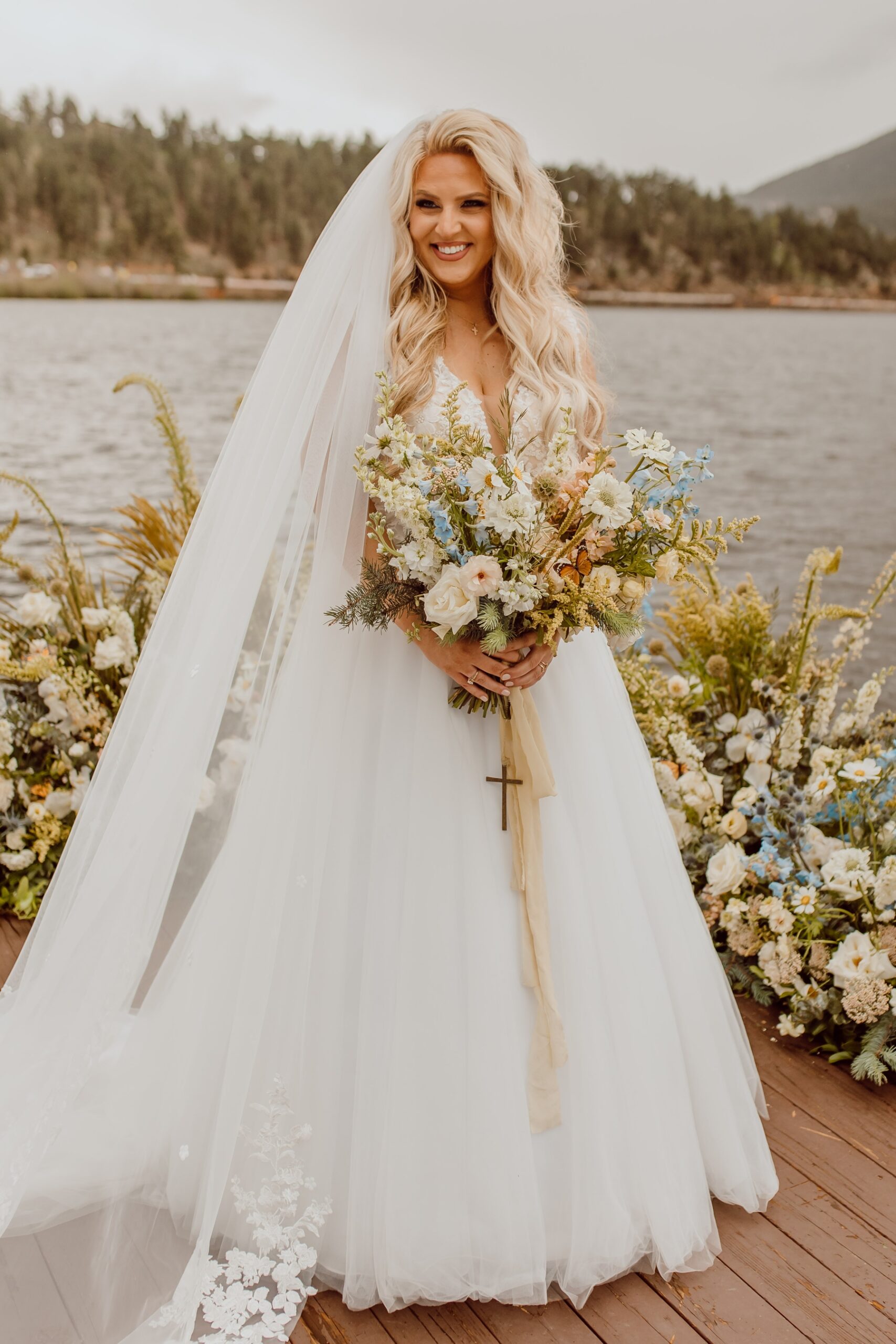 Bride holding wildflower bouquet standing on deck at Evergreen Lake House