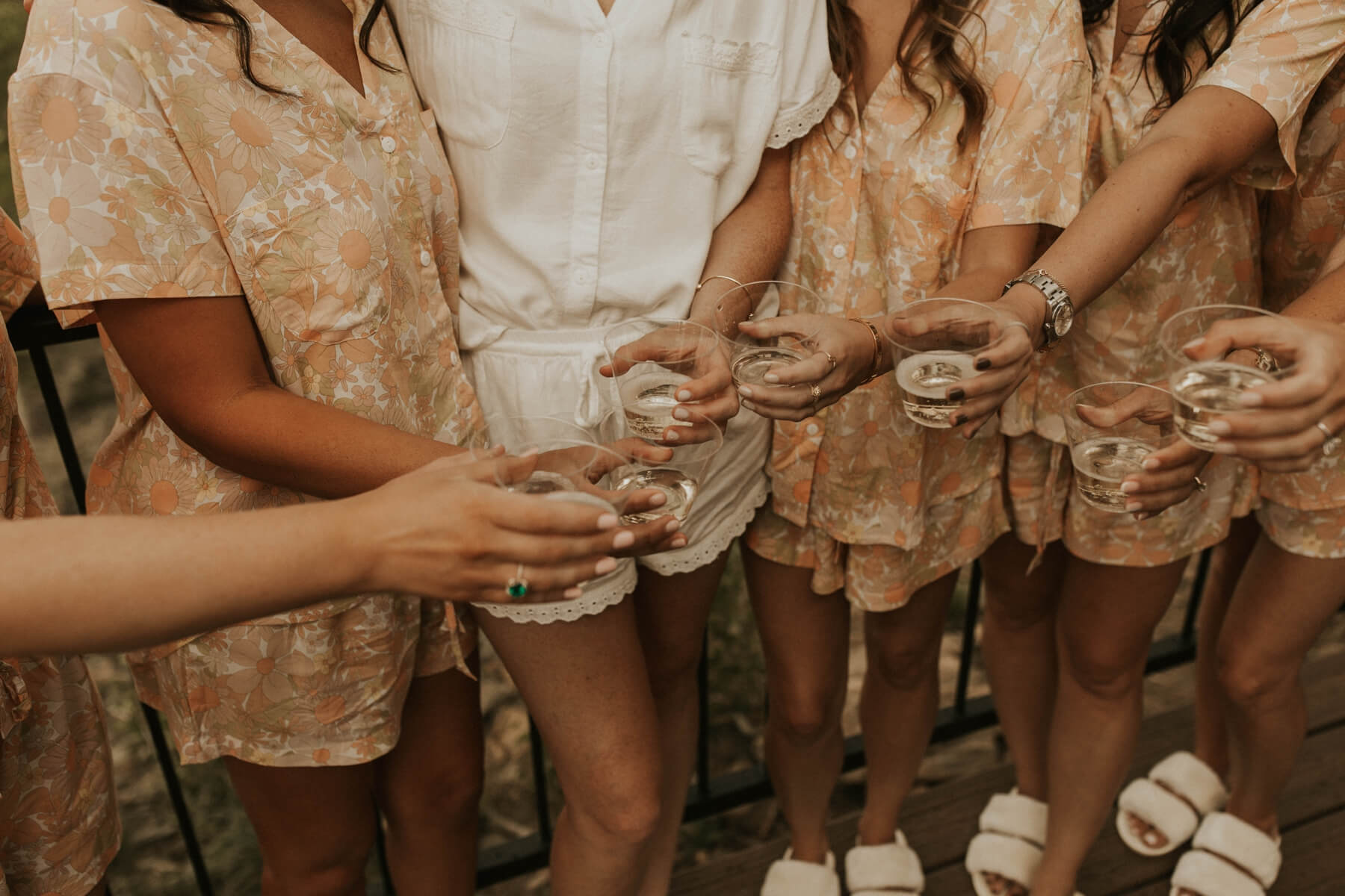 Bridesmaids and bride wearing matching pajamas and slippers doing a champagne toast
