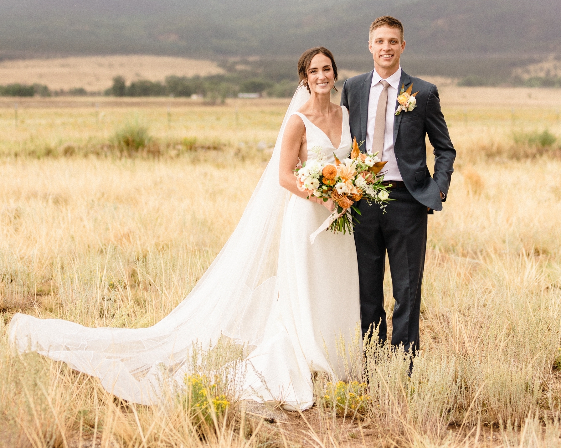 Bride and groom standing in field in Colorado