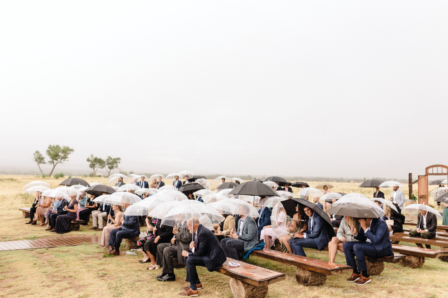 Guests sitting in the rain during wedding ceremony at The Barn at Sunset Ranch