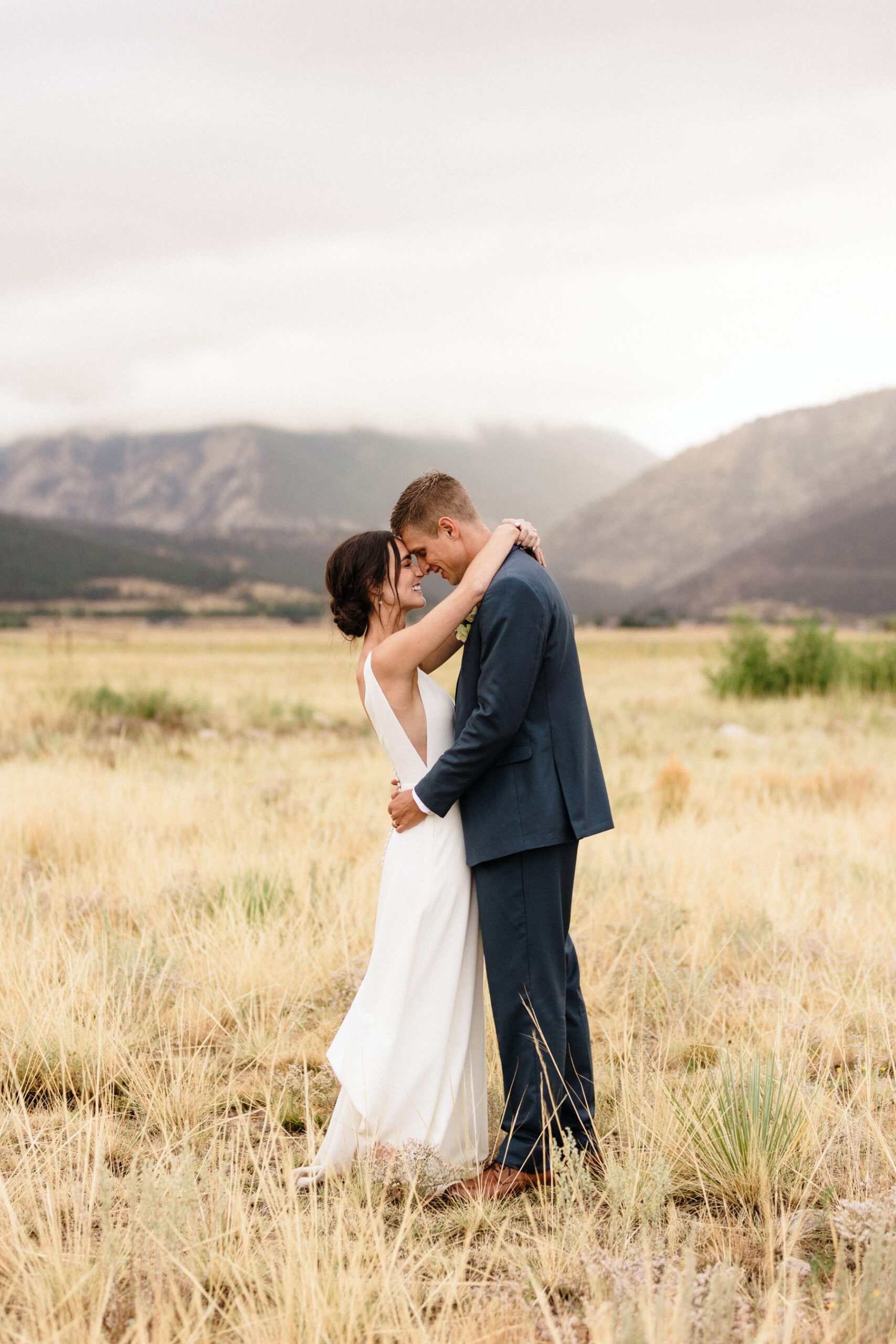 Bride and groom touching foreheads in field at The Barn at Sunset Ranch