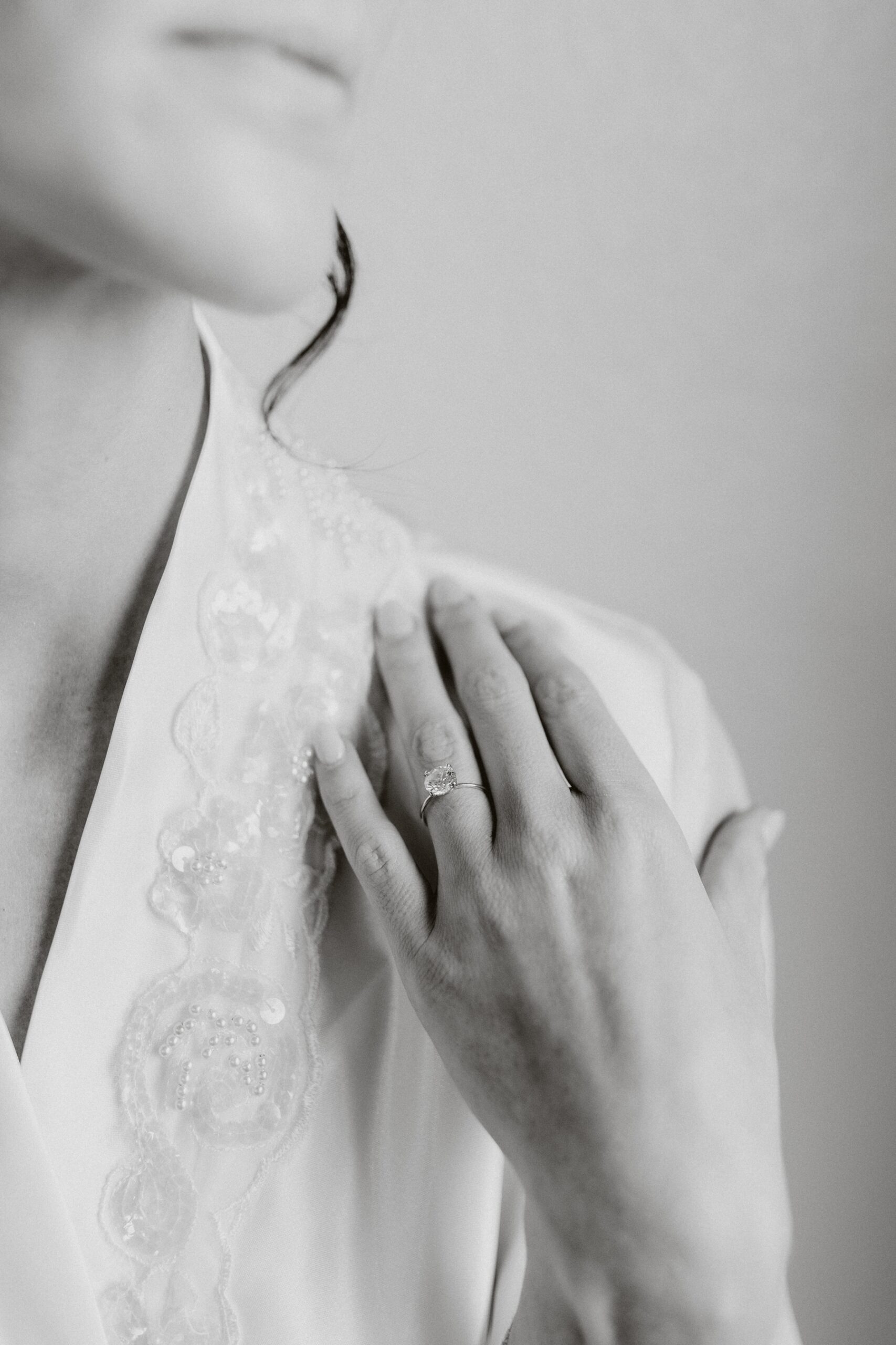 Bride resting hand on her shoulder with engagement ring in focus