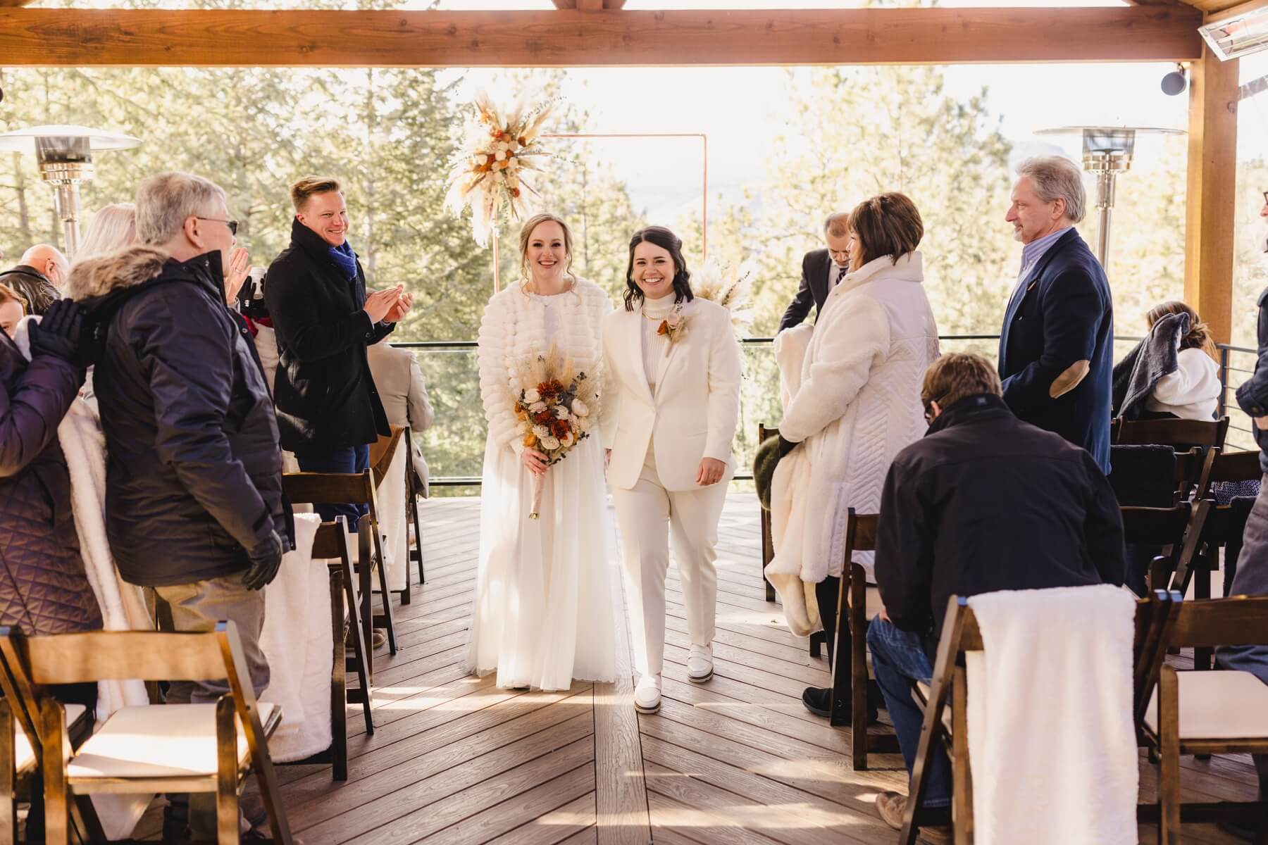 Couple walking down the aisle in white wedding dress and white suit